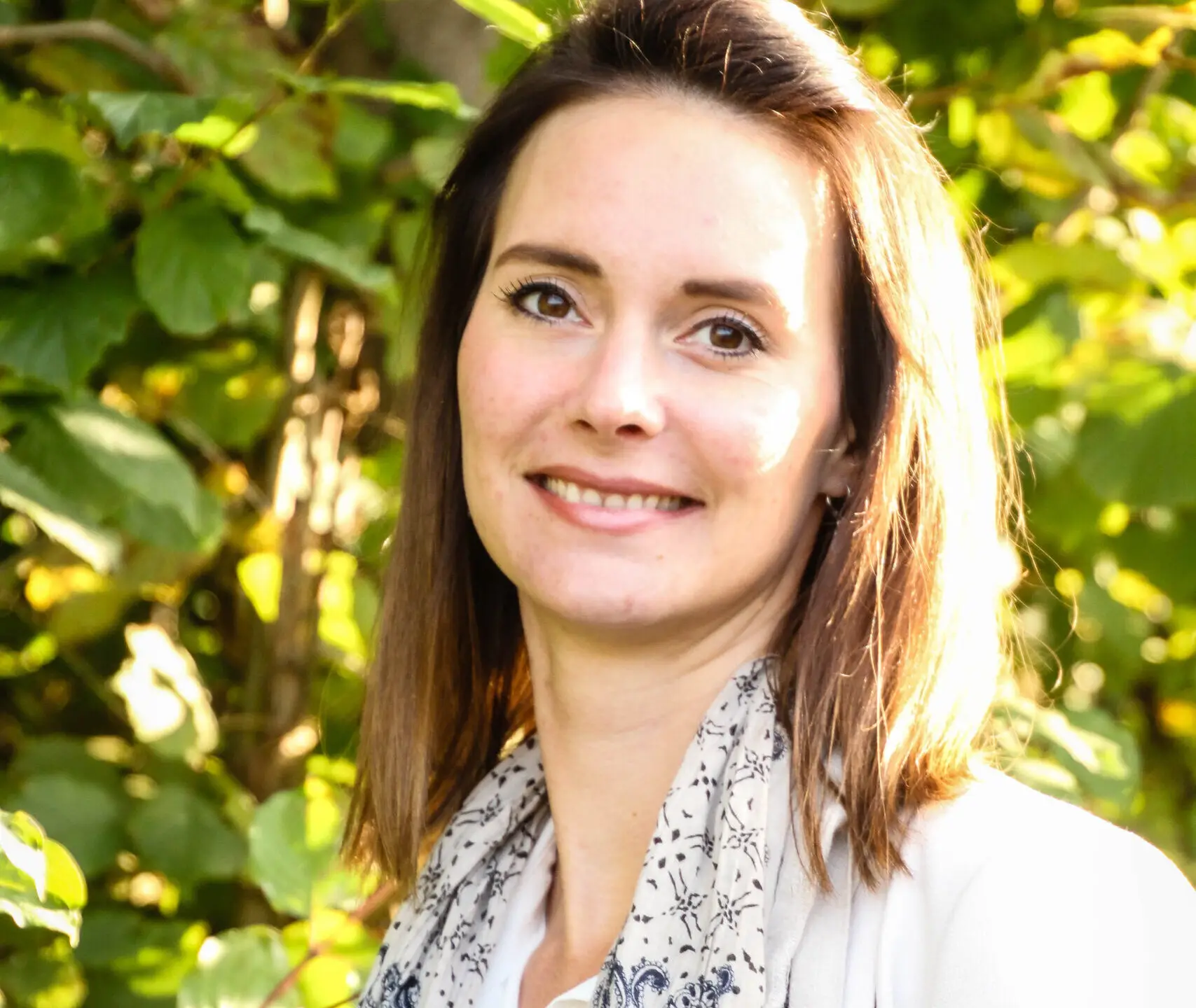 Portrait einer braunhaarigen Frau. Sie lacht in die Kamera.