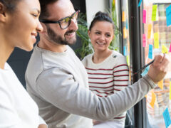 Ein Meeting zwischen drei Personen an einem Fenster mit post-its