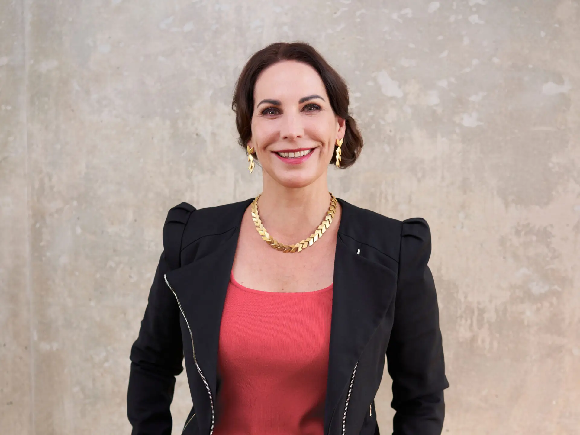 Portrait von Katrin Winkler in einer schwarzen Jacke und mit goldenem Schmuck.