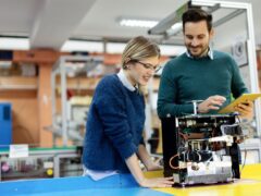 Ein Mann und eine Frau sehen sich das Innenleben eines technischen Gerätes an.