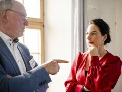 Eine Frau im roten Kleid, Prof. Dr. Katrin Winkler und ein Mann im blauen Anzug, Dr. Wolfgang Hauke, unterhalten sich.