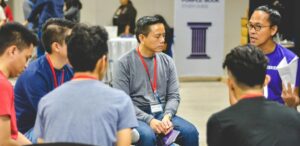 Teilnehmer eines Programms für Master Beratung, Organisationsentwicklung & Coaching sitzen im Kreis und tauschen sich im Rahmen einer Coaching-Session aus Master Coaching