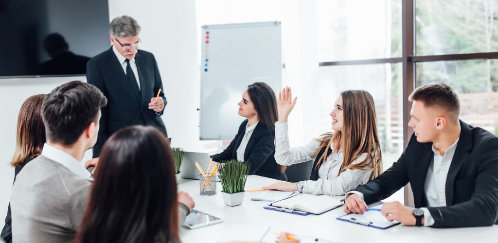 Eine Gruppe von Executive-MBA-Absolventen diskutiert in einem Konferenzraum über Karrieremöglichkeiten. Executive MBA