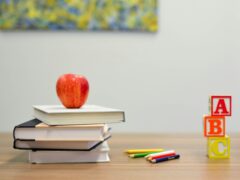 Ein Stapel Bücher mit einem Apfel drauf, ein paar Stifte und drei Bausteine die "ABC" bilden - ein Sinnbild für Bildung und hier genutzt um Unternehmen als Bildungsakteure abzubilden