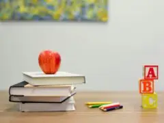 Ein Stapel Bücher mit einem Apfel drauf, ein paar Stifte und drei Bausteine die "ABC" bilden - ein Sinnbild für Bildung und hier genutzt um Unternehmen als Bildungsakteure abzubilden