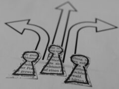 Drei aus bedrucktem Papier ausgeschnittene Figürchen und drei Pfeile in unterschiedliche Richtungen. Sinnbildlich für die Frage, wer zur Zielgruppe für den Master Wirtschaftspsychologie gehört