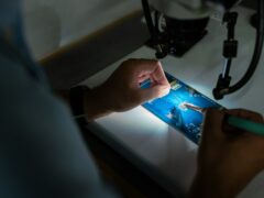 Man sieht einen Blick über die Schulter eeiner PErson, die eine Platine lötet, ein Sinnbild für Technik für Betriebswirte