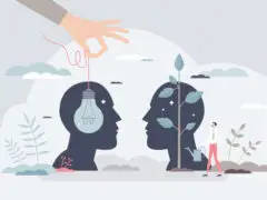 Ein Bild, um Business Coaching im Unternehmenskontext darzustellen. Zwei stilisierte Köpfe, der linke hat eine Glühbirne im Kopf, die an einem Faden von einer Hand gehalten wird, die von außerhalb des Bildes kommt, der andere hat eine Pflanze, die von einem kleinen Menschen gewässert wird.