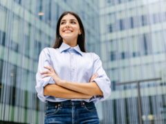 Wer braucht Wertschöpfung in der Krise: junge Führungskraft mit klarer Haltung vor modernem Unternehmensgebäude