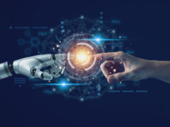 Was ist künstliche Intelligenz? Eine menschliche Hand und eine Roboter-Hand berühren sich an den Zeigefingern.