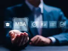 Das Bild zeigt ein Motiv zum Thema akademische Weiterbildung, Management-Qualifikation und Karriereentwicklung. Im Zentrum steht eine Hand in offener Geste, über der eine Reihe von blau leuchtenden, digitalen Icons schwebt. Das vergrößerte Haupt-Icon zeigt den Schriftzug „MBA“, flankiert von Symbolen für Doktorhut, Zielscheibe, Präsentation/Führung, Buch und Haken/Abschluss. Im unscharfen Hintergrund ist ein Mann im dunklen Anzug zu sehen. Das Bild symbolisiert Themen wie Executive Education, Studium, Führungskräfteentwicklung und professionelles Skill-Building.
